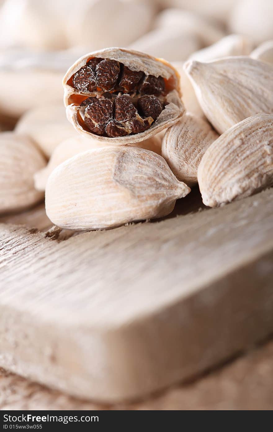 White cardamom pods on old wood, one opened, super macro, shallow DOF. White cardamom pods on old wood, one opened, super macro, shallow DOF