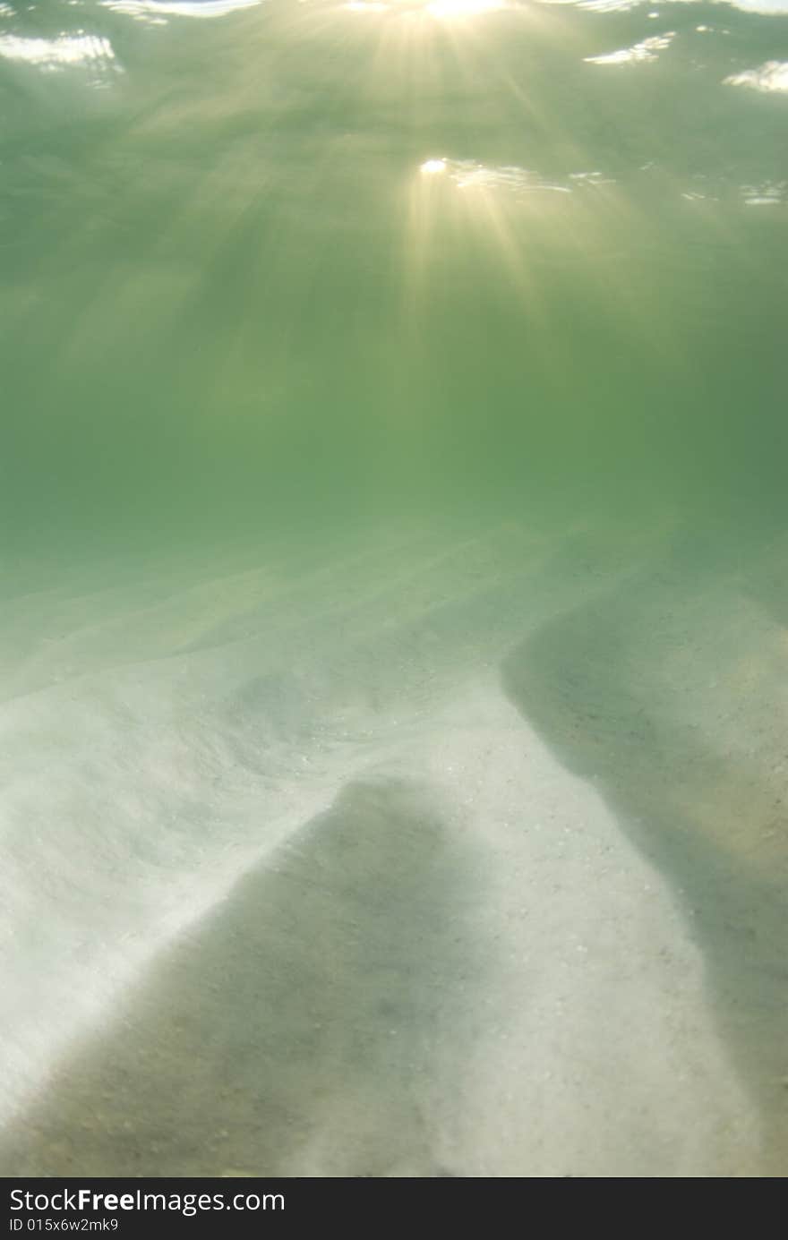 A view of the rippled ocean floor, the action on the surface, and the sky and golden sunset rays breaking through the water. Double top sunrays. A view of the rippled ocean floor, the action on the surface, and the sky and golden sunset rays breaking through the water. Double top sunrays.