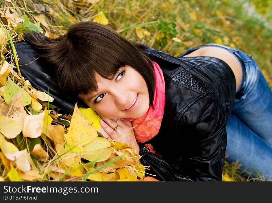 Happy cute girl on the grass covered with yellow leaves in the park. Happy cute girl on the grass covered with yellow leaves in the park