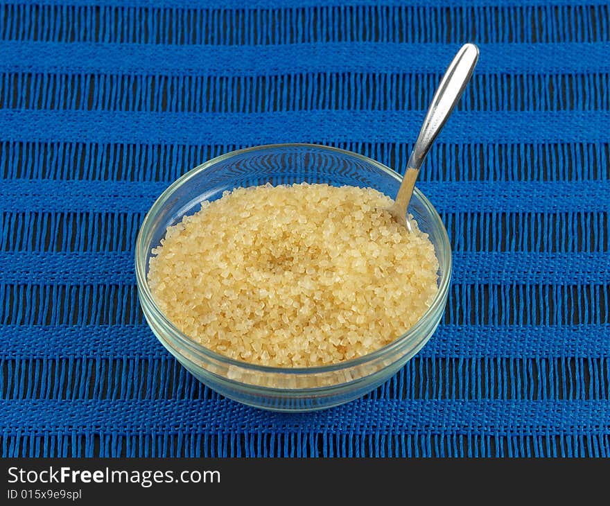 Raw sugar in clear glass bowl and spoon