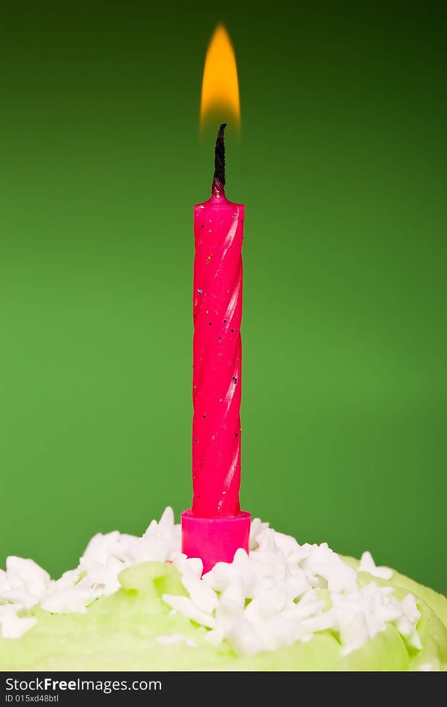 Small green cake with a single candle on a green background