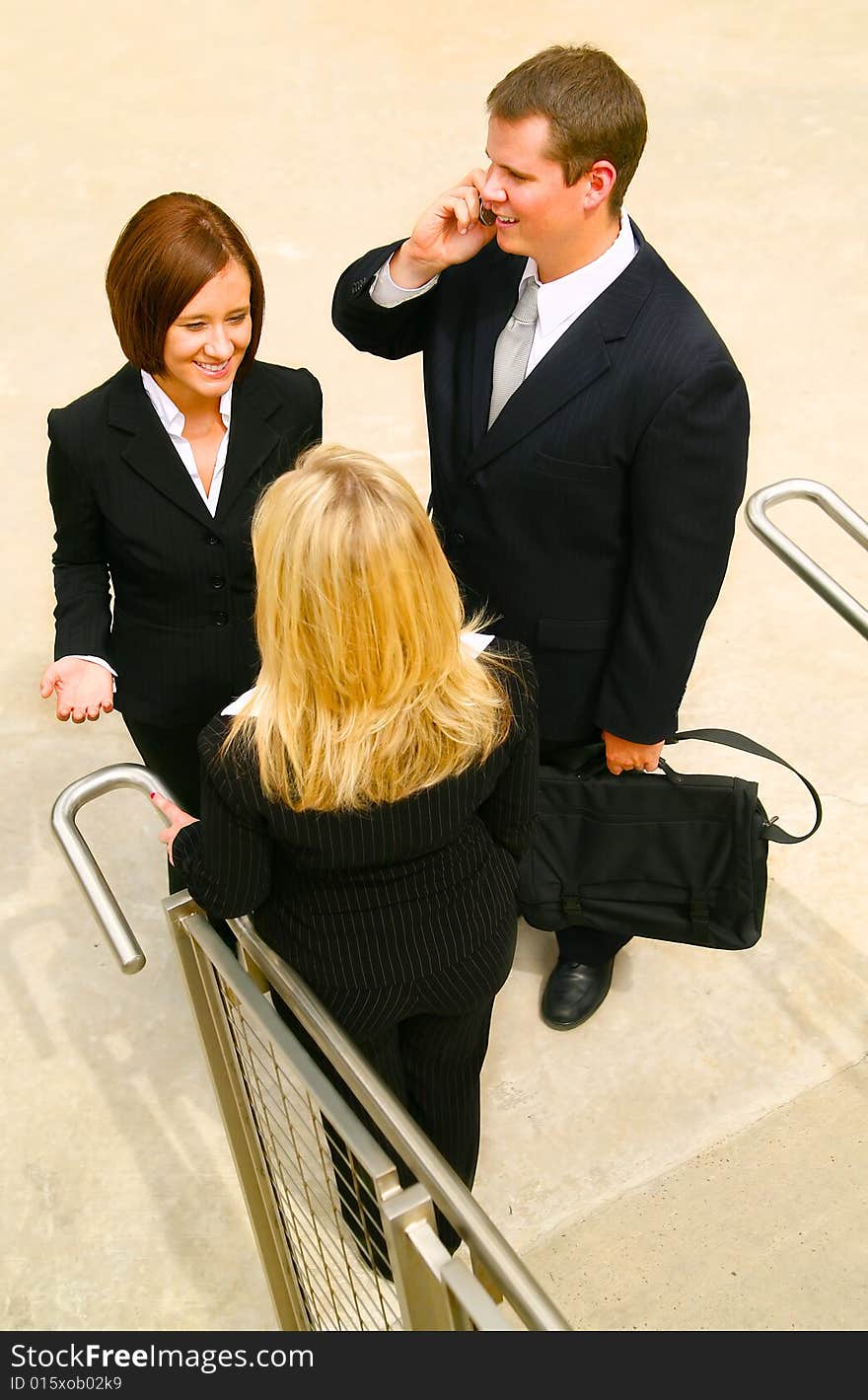 Business man talking on the phone and two other business women having a chat near stair. Business man talking on the phone and two other business women having a chat near stair