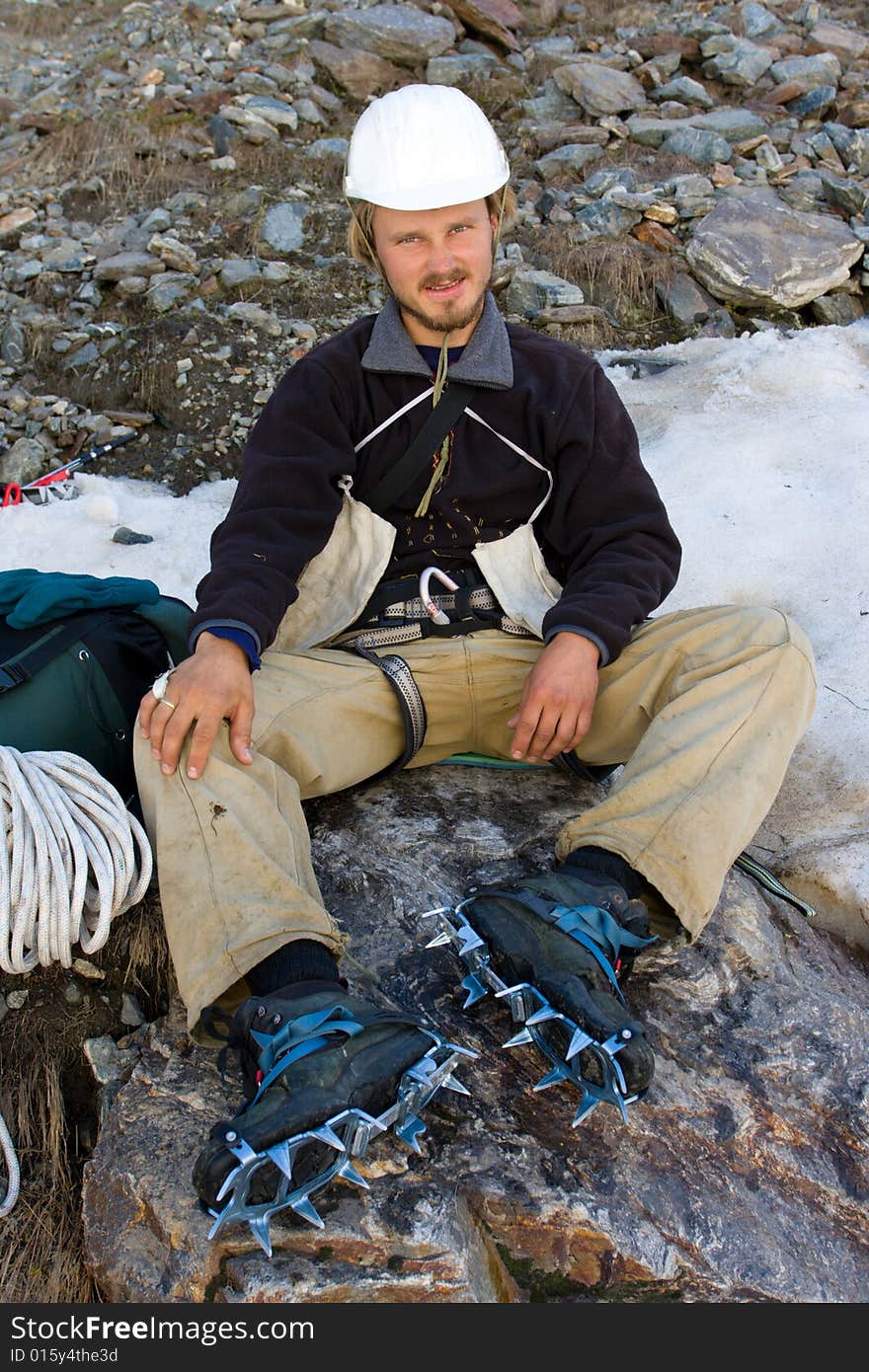 Climber in helmet and crampon sitting on stone. Climber in helmet and crampon sitting on stone