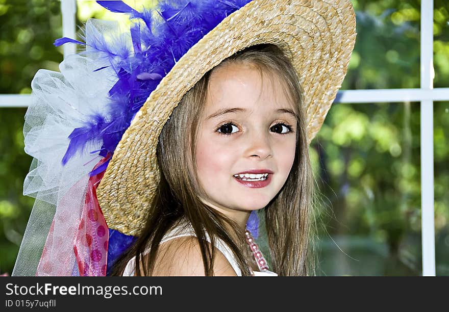 Little girl dressed up in a hat that has ribbons and feathers wrapped around it. Little girl dressed up in a hat that has ribbons and feathers wrapped around it.