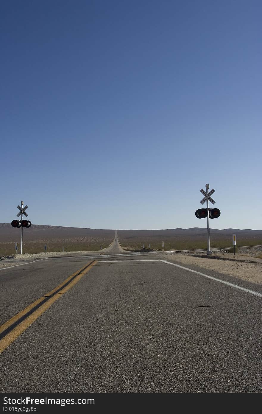 A point were a train can cross the road in death valley. In the back you see the endless road going on and on. A point were a train can cross the road in death valley. In the back you see the endless road going on and on.