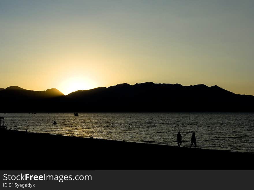 A sunset with people walking over the beach