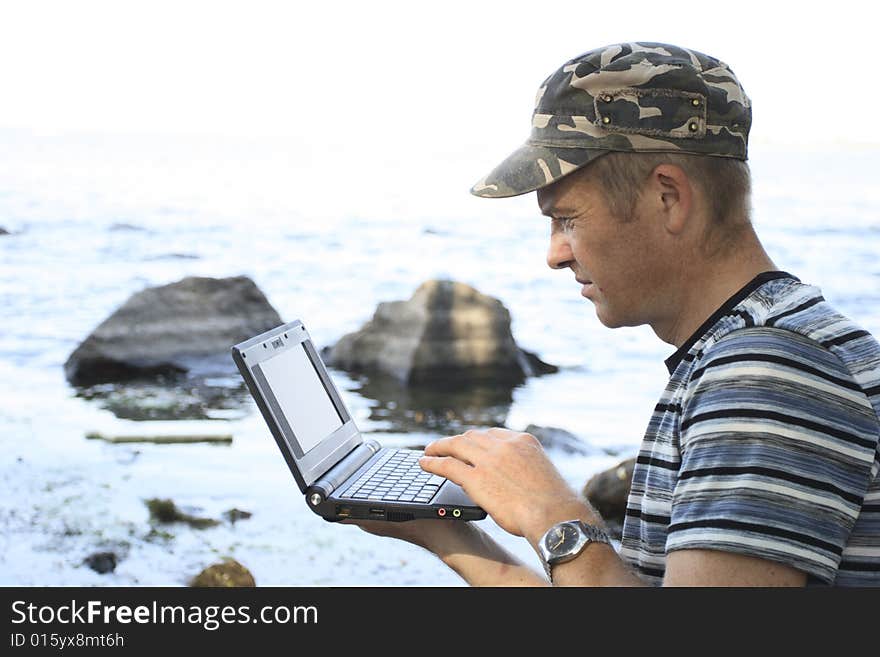 Man works at notebook sitting on stone