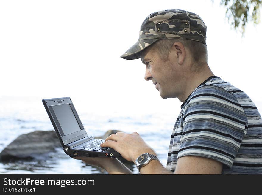 Man works at notebook sitting on stone