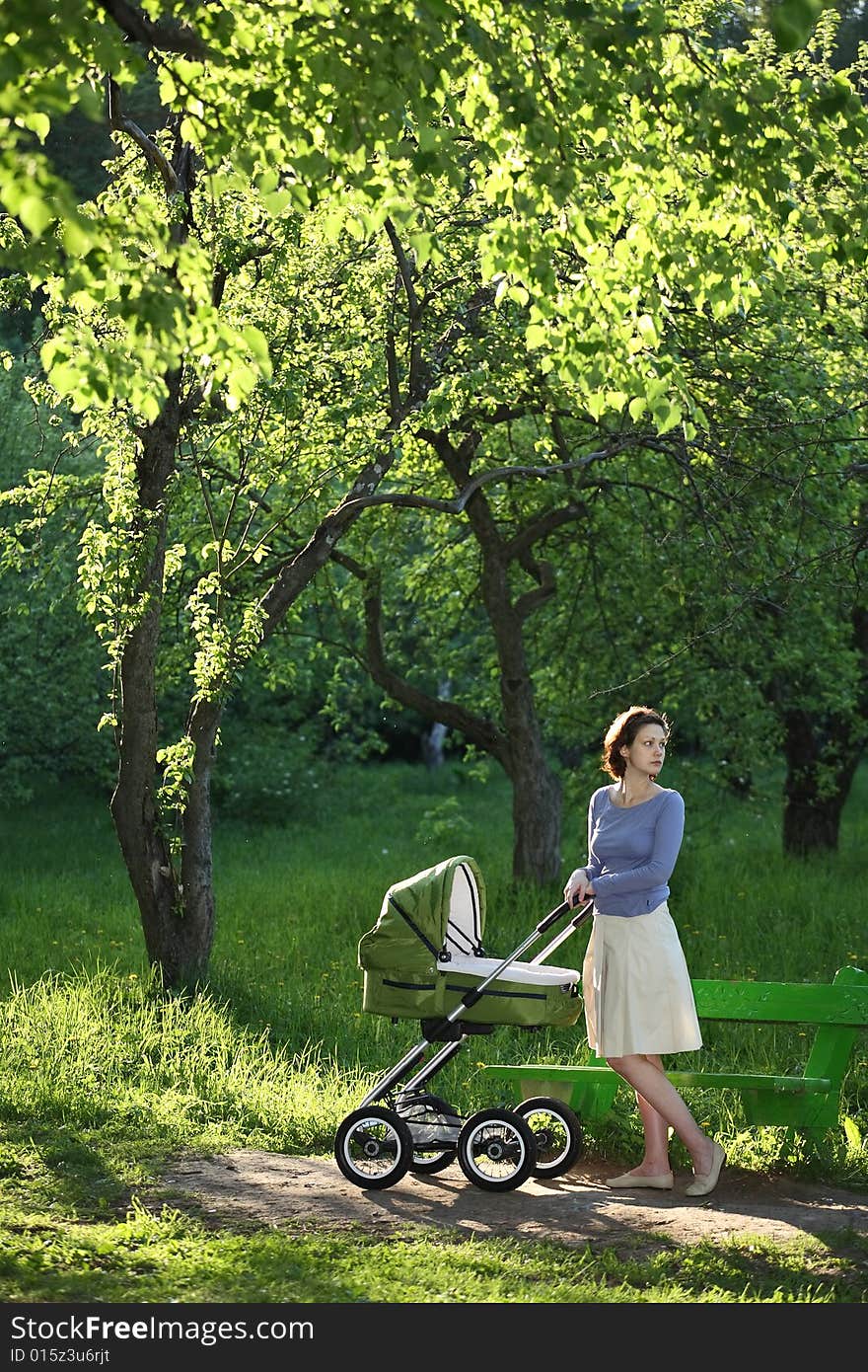 Mother with baby carriage in summer park. Mother with baby carriage in summer park