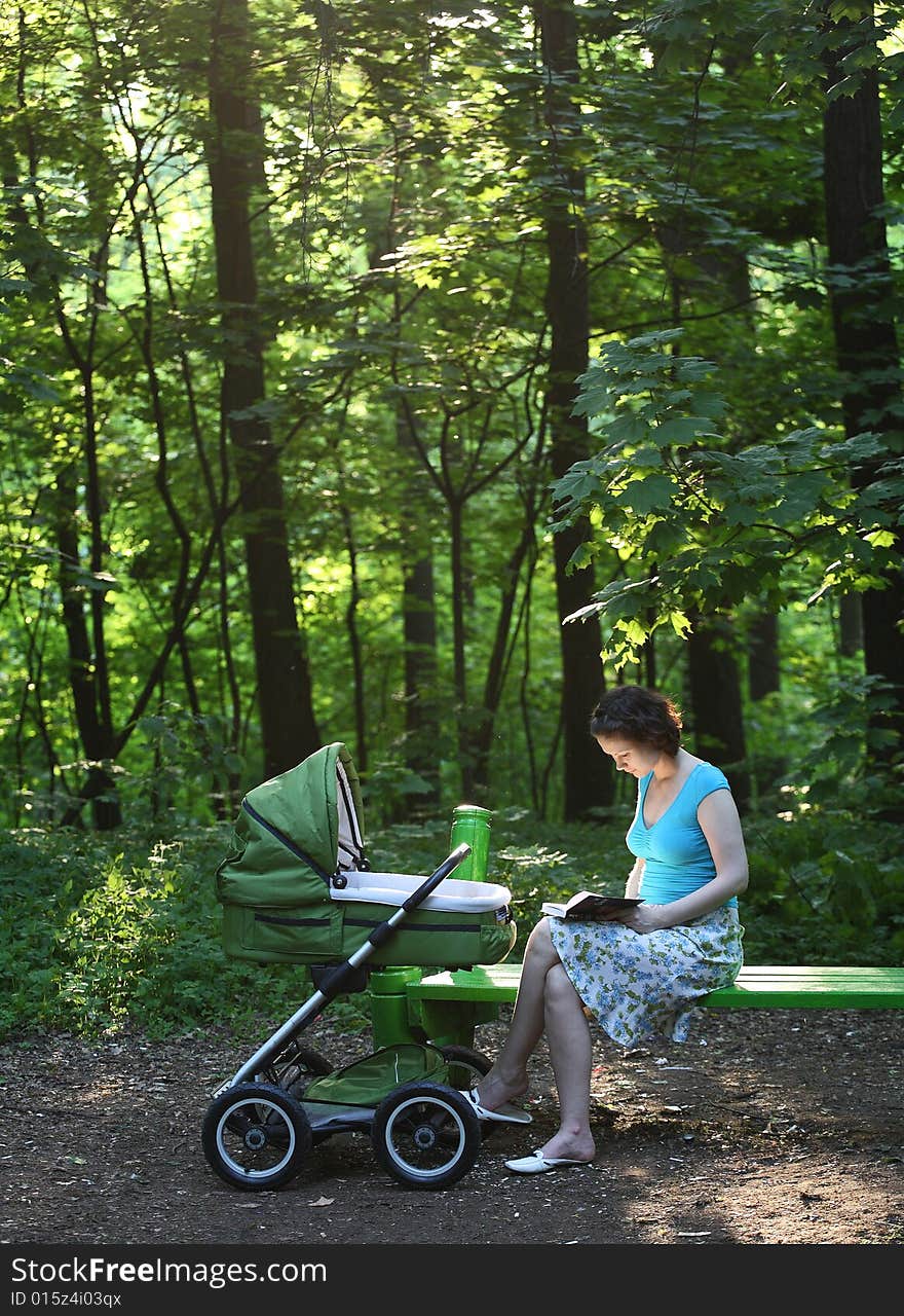 Mother with baby carriage in the summer park