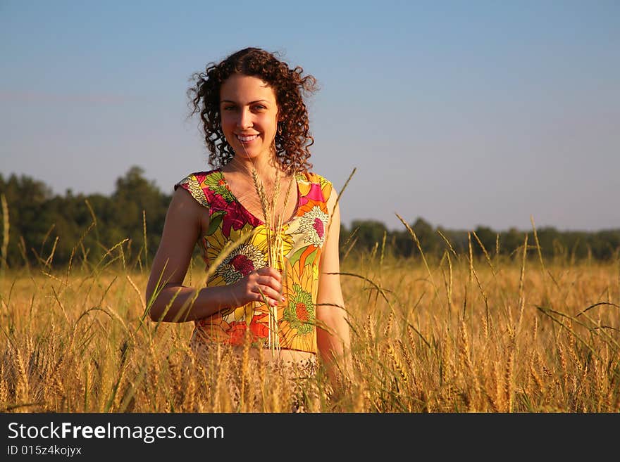 Young woman with earns stands on a wheaten field