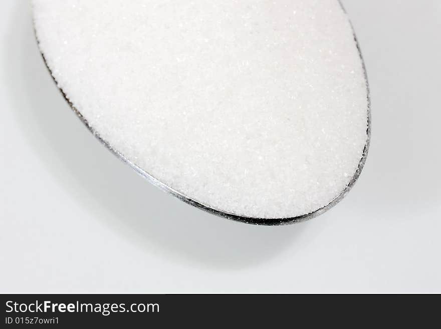 A macro shot of white sugar in a spoon (focus on the front area of the sugar). A macro shot of white sugar in a spoon (focus on the front area of the sugar)