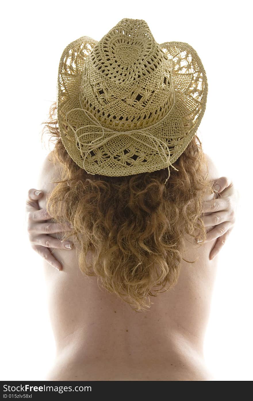 Back view of a woman hugging herself and naked from the waste up wearing a cowboy hat