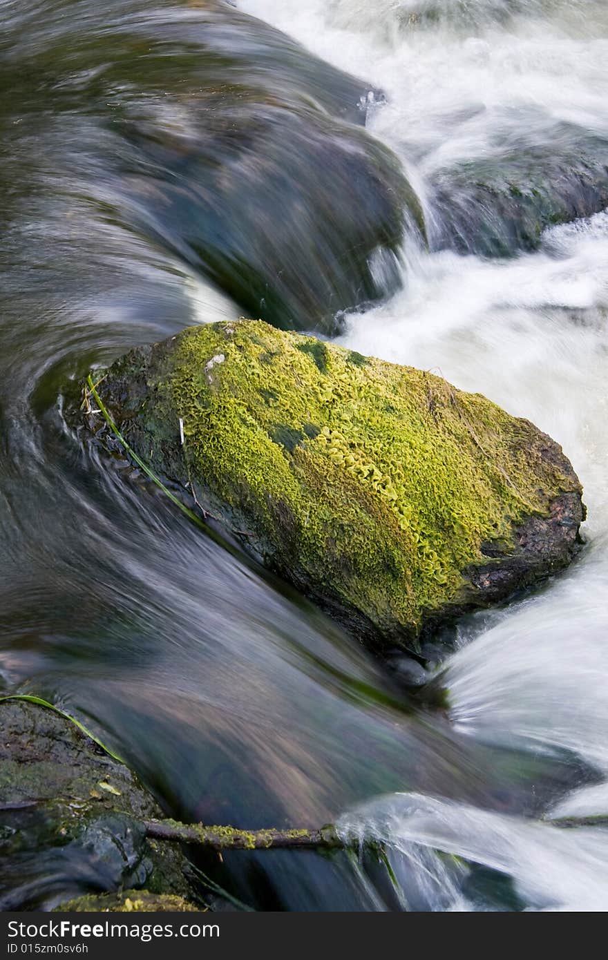 Stone covered with a moss in the falling rough river. Stone covered with a moss in the falling rough river