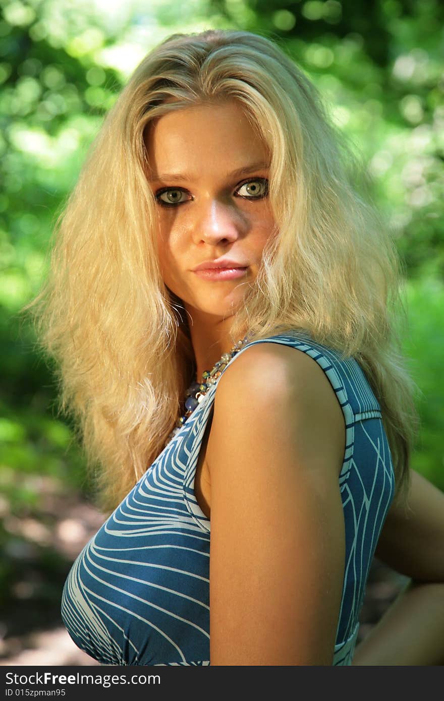 Young beautiful blonde with black eyes in dark in wood