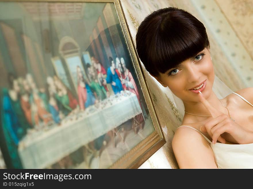 Mysterious bride is standing near picture with smile