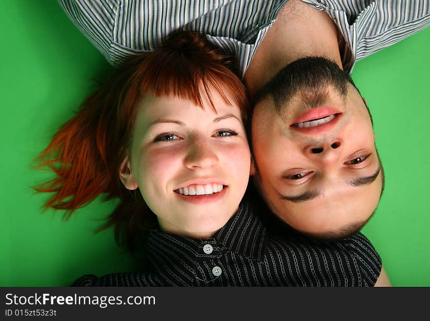 Girl with red hair and guy lie head to head on green