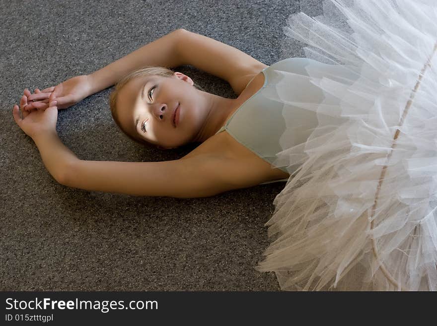 Smiling ballerina is relaxing on the floor. Smiling ballerina is relaxing on the floor