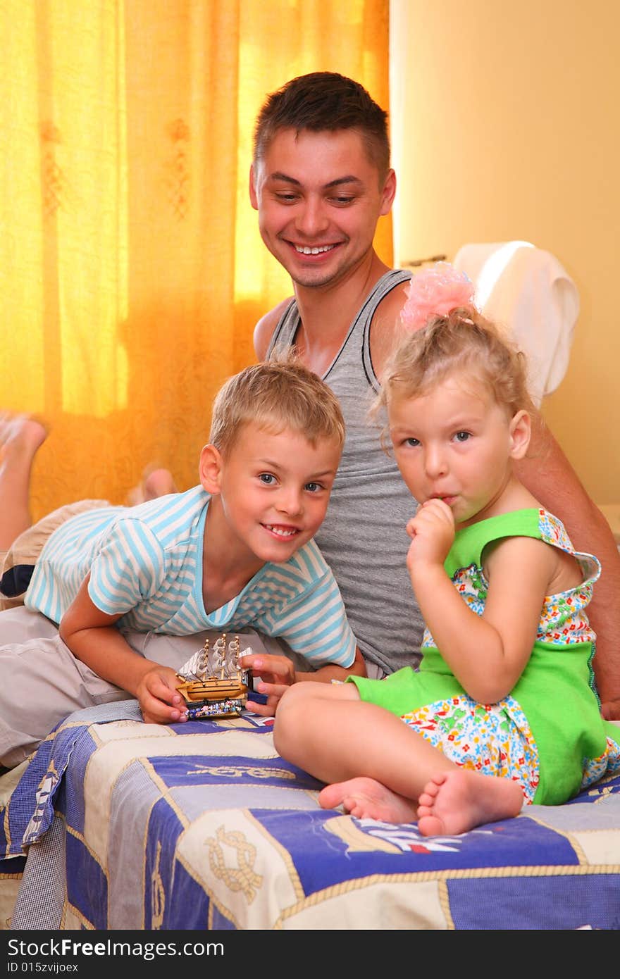 Children with father sitting on bed in room