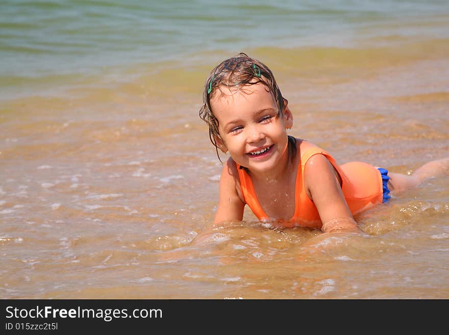 Little girl lies in waves