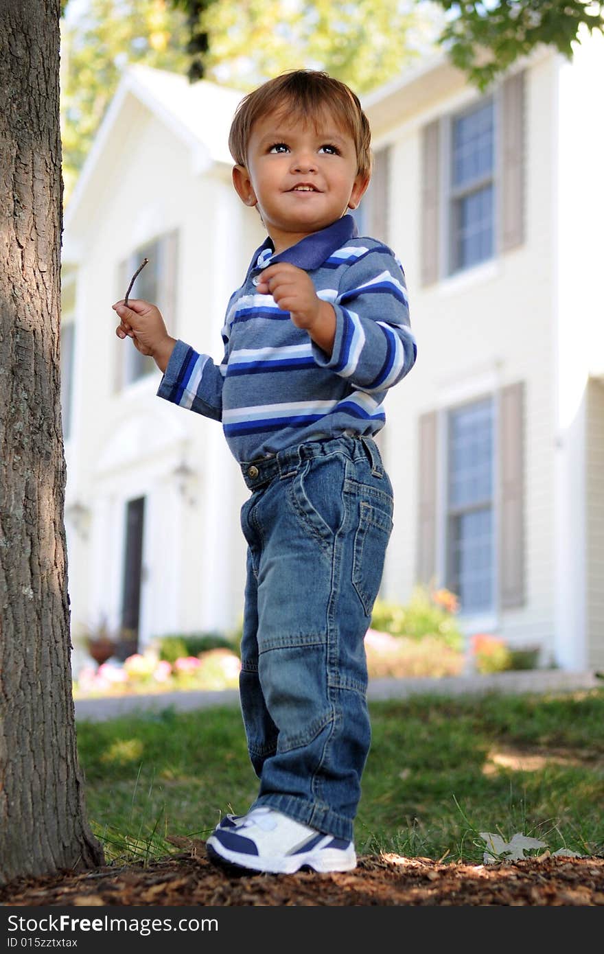 A happy 18-month-older playing in his front yard with his suburban house in the background. A happy 18-month-older playing in his front yard with his suburban house in the background.