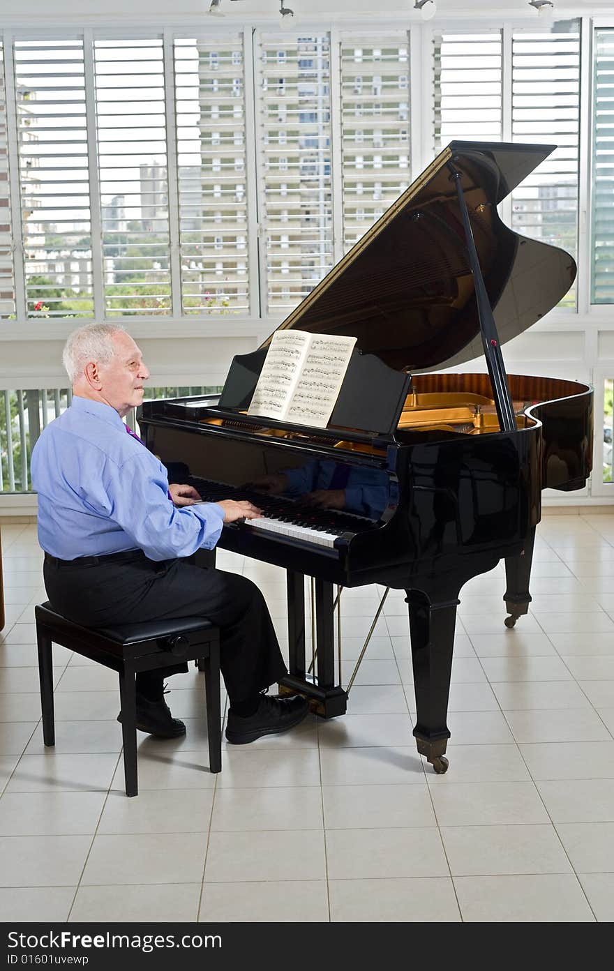 Senior man playing on a grand piano at home. Senior man playing on a grand piano at home