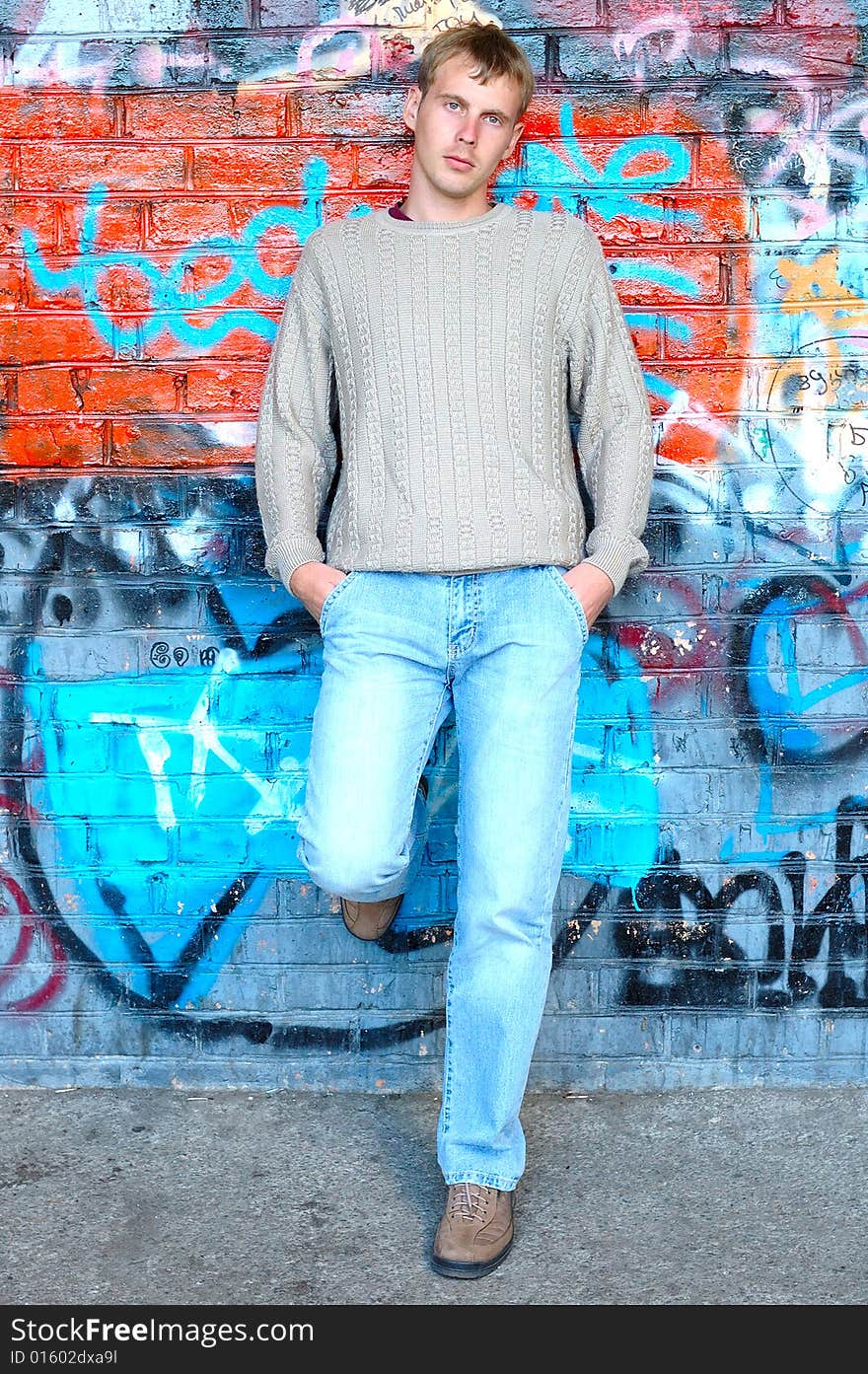 Young stylish man stand near graffiti brick wall.