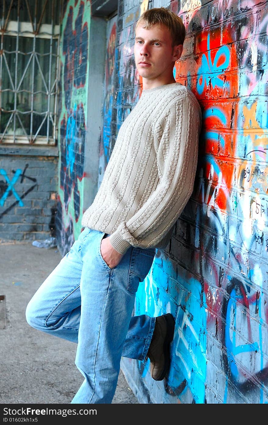 Young stylish man stand near graffiti brick wall.