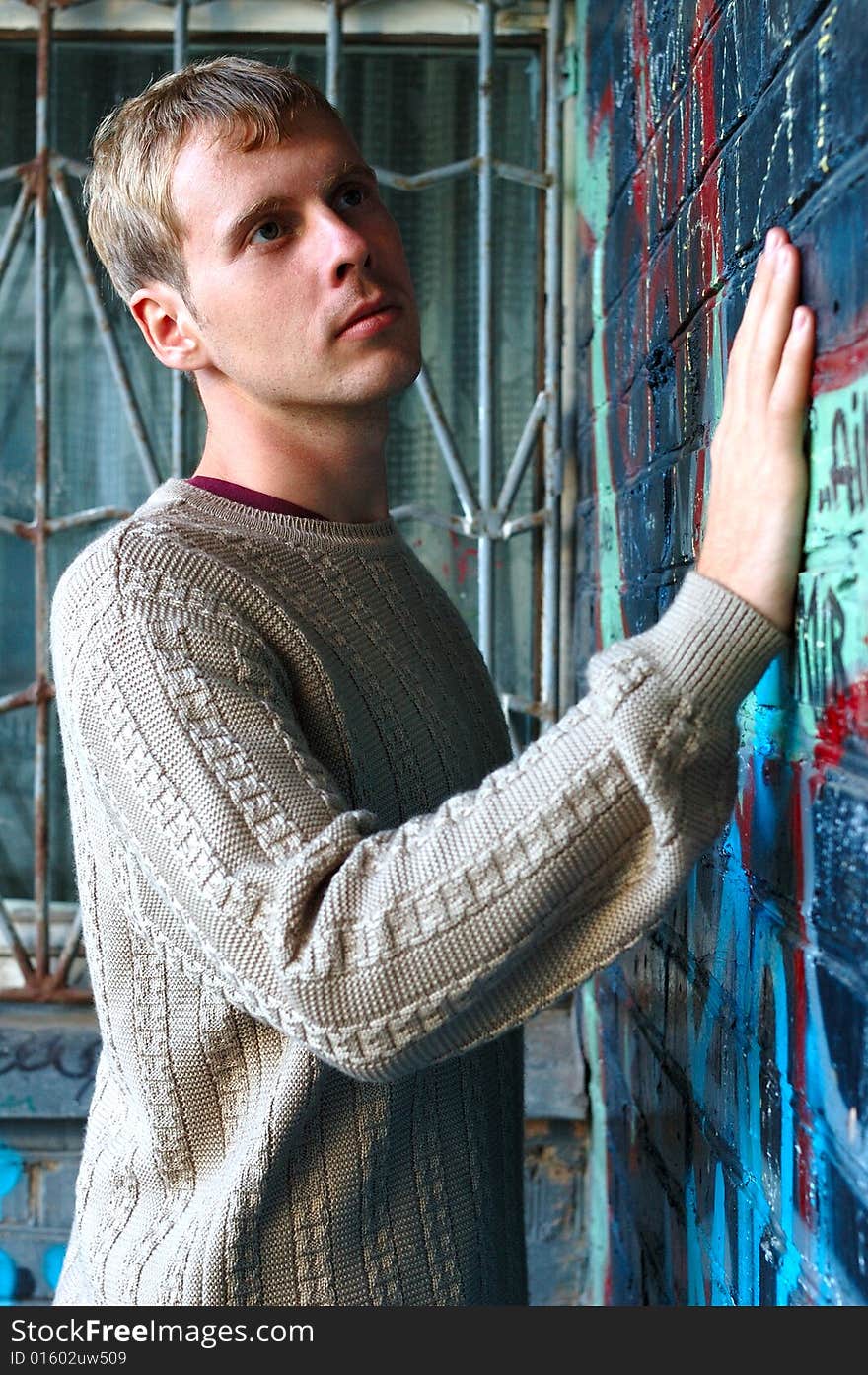 Young stylish man with blonde hair stand near graffiti brick wall. Young stylish man with blonde hair stand near graffiti brick wall.