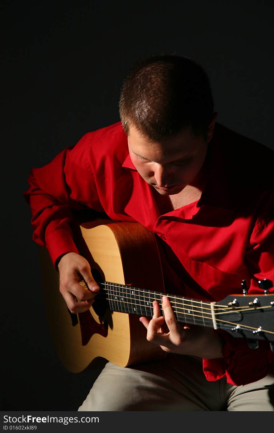 Guitarist in red shirt on dark
