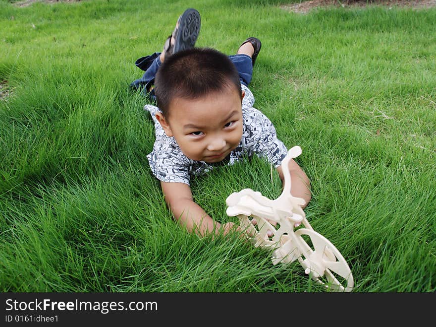 The boy grovels on the meadow playing with his toy happily. The boy grovels on the meadow playing with his toy happily.