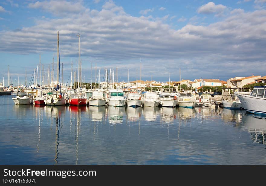 Many docked sail and motor yachts at sea pier, under cloudy sky, horizontal. Many docked sail and motor yachts at sea pier, under cloudy sky, horizontal