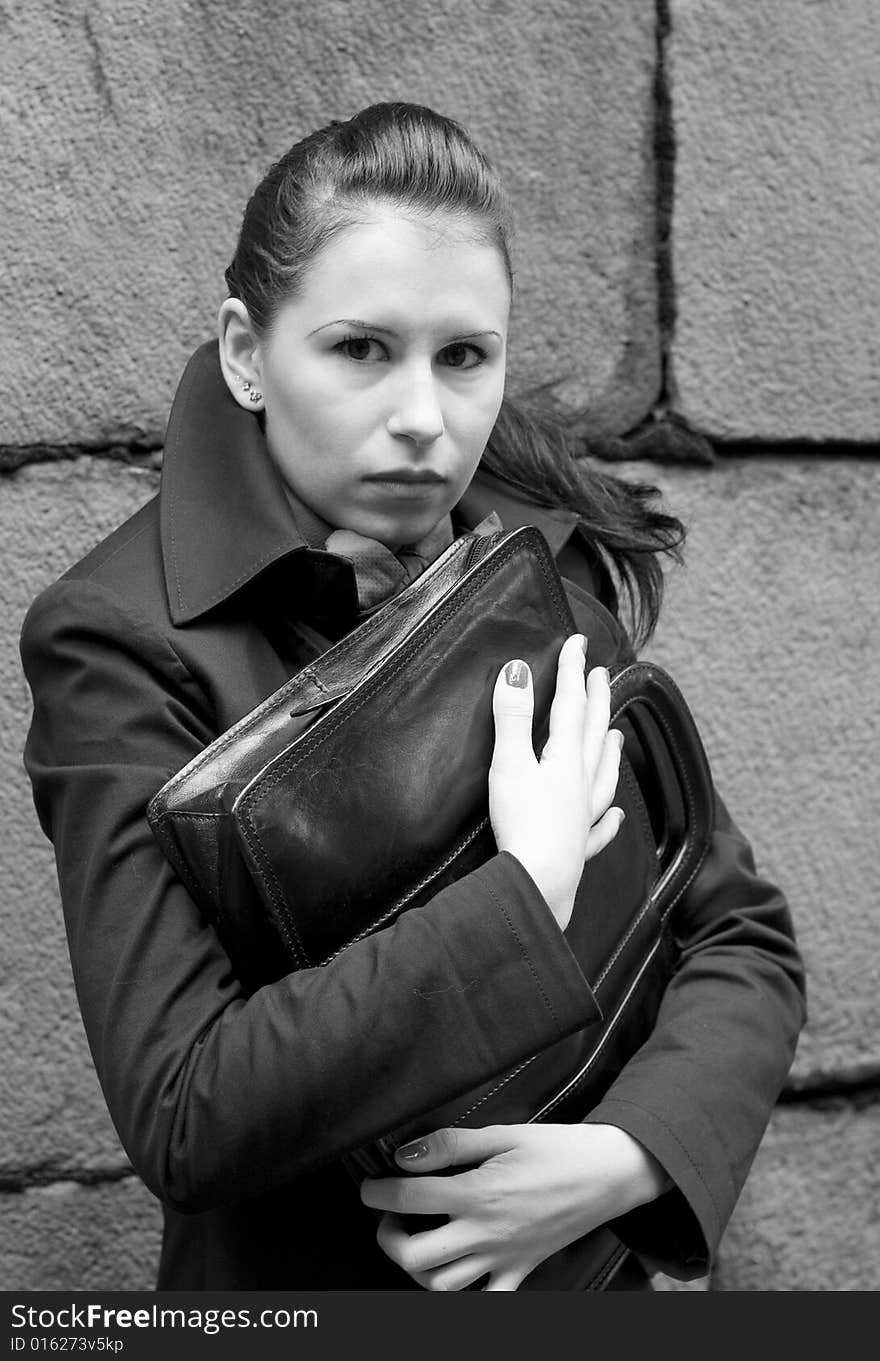 Woman in black holding portfolio near brick wall