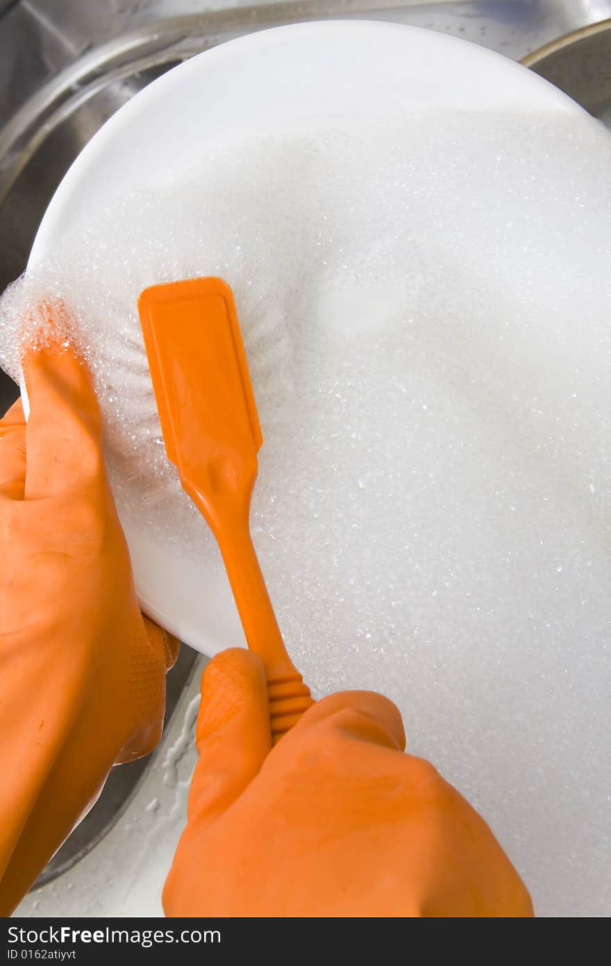 Hands in gloves washing dishes at the kitchen