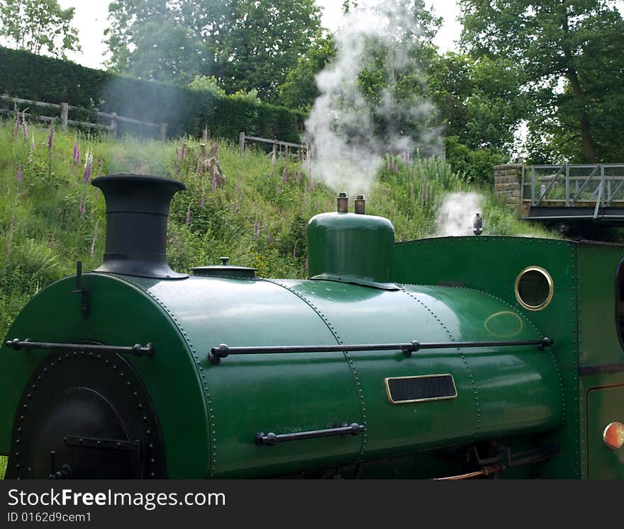 A green steam train  at a station