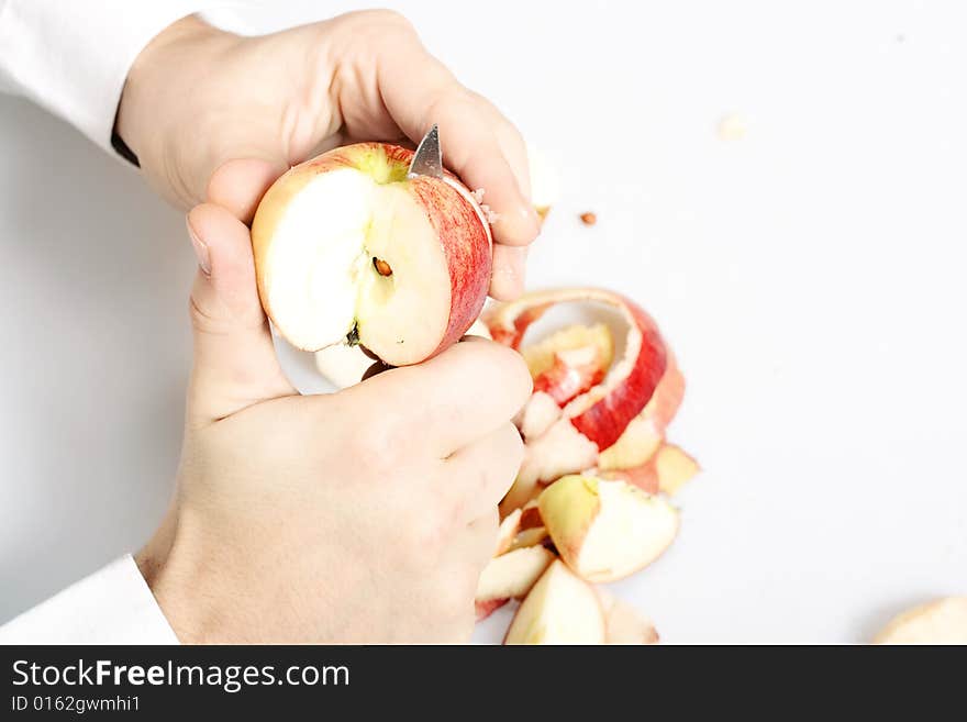 Apple cut by knife in hands.