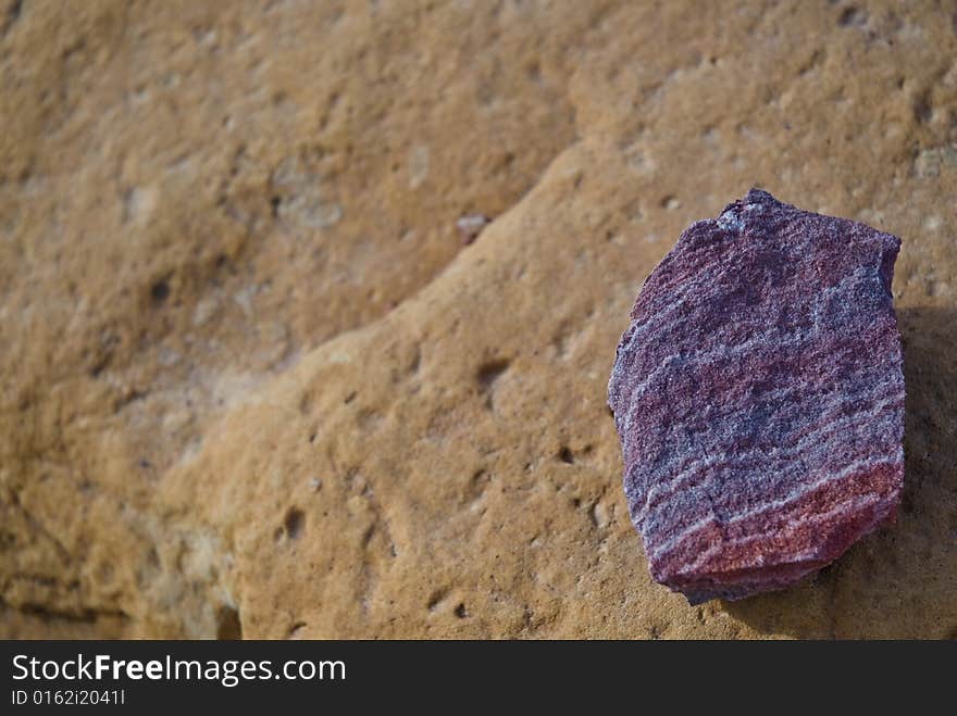 A purple rock on a brown rock. Found in Petra, Jordan.