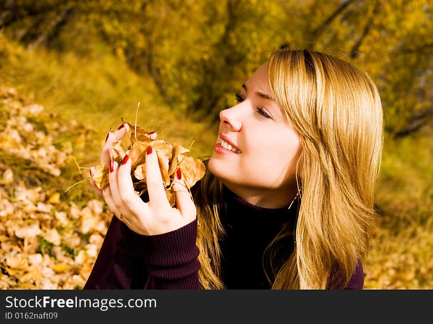 Pretty girl with yellow leaves in the park