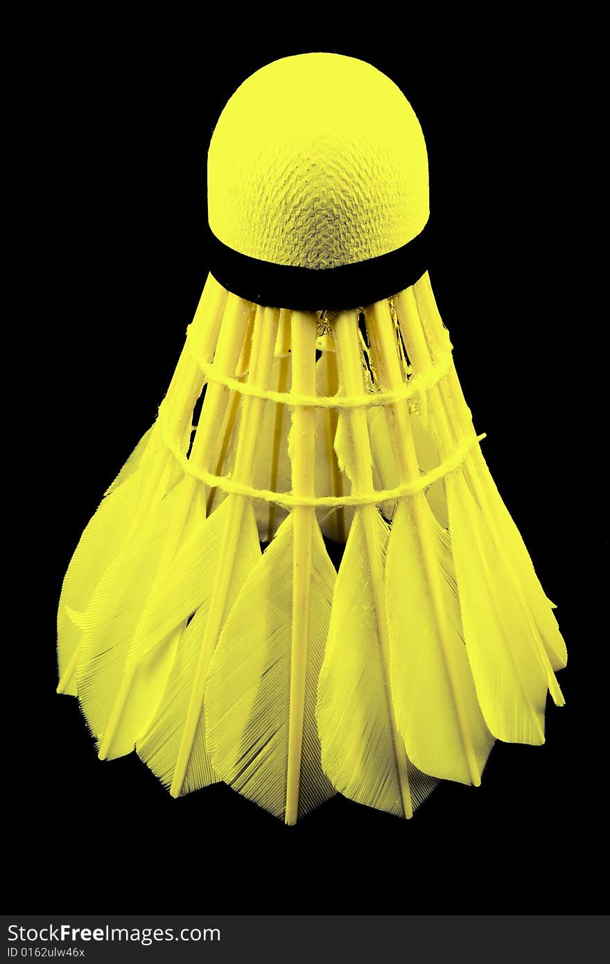 A yellow shuttlecock with feathers on the black background