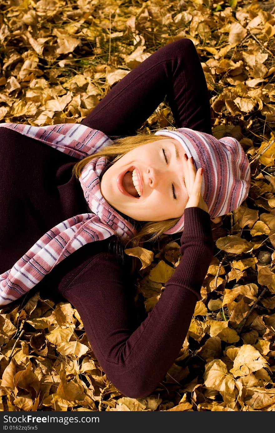 Happy girl on the grass covered with yellow leaves in the park. Happy girl on the grass covered with yellow leaves in the park