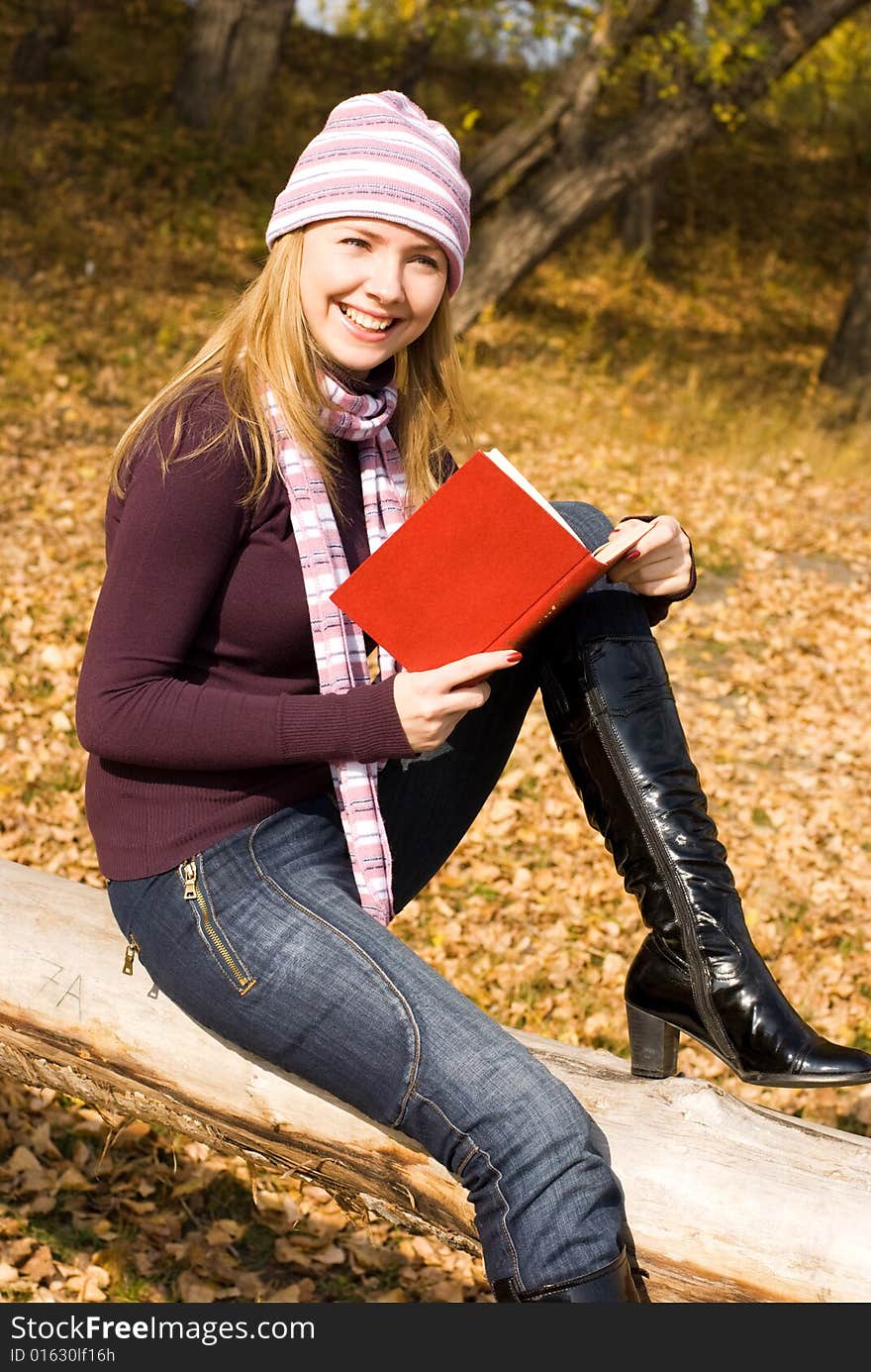 Pretty girl sitting on the tree and reading a book in the park. Pretty girl sitting on the tree and reading a book in the park