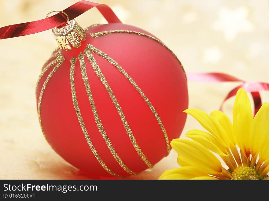 Christmas red ball with yellow flower on golden background.