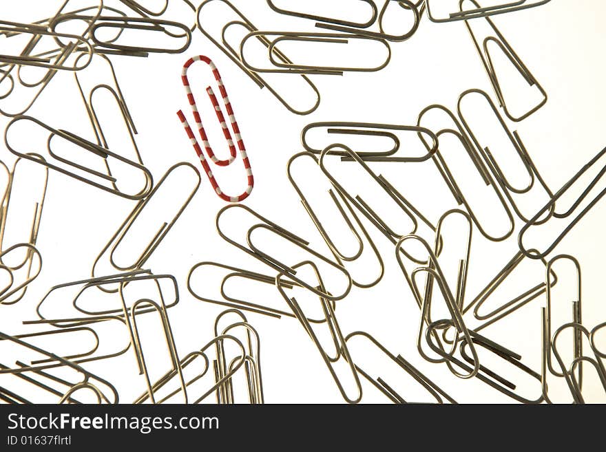 Red and white paperclip in a group of metal paperc