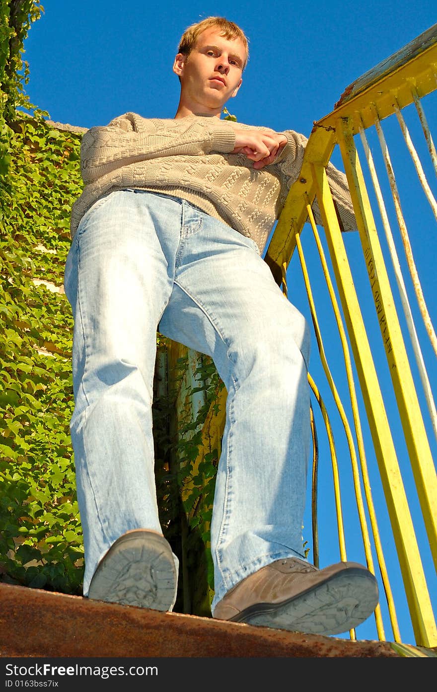 Young stylish blonde man stay on stairs near overgrown with vine wall. Young stylish blonde man stay on stairs near overgrown with vine wall.