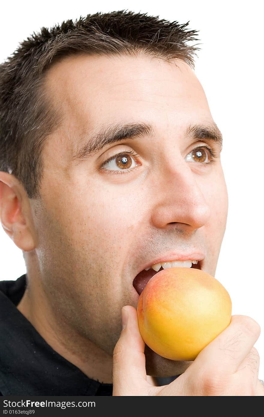 Young man, eating a peach, holding it between his teeth. Young man, eating a peach, holding it between his teeth