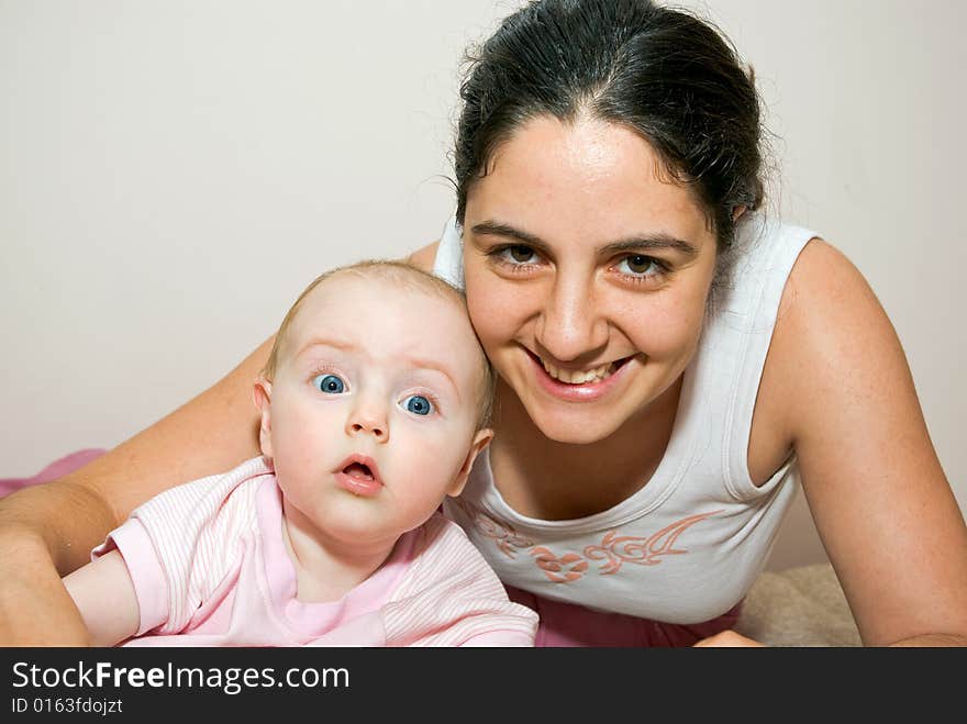 Mother and baby girl, enjoying the time together on a couch. Mother and baby girl, enjoying the time together on a couch