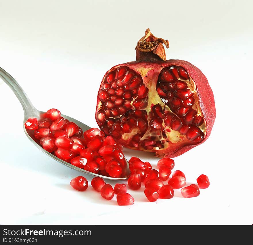 Ripe pomegranate and spoon isolated on white background