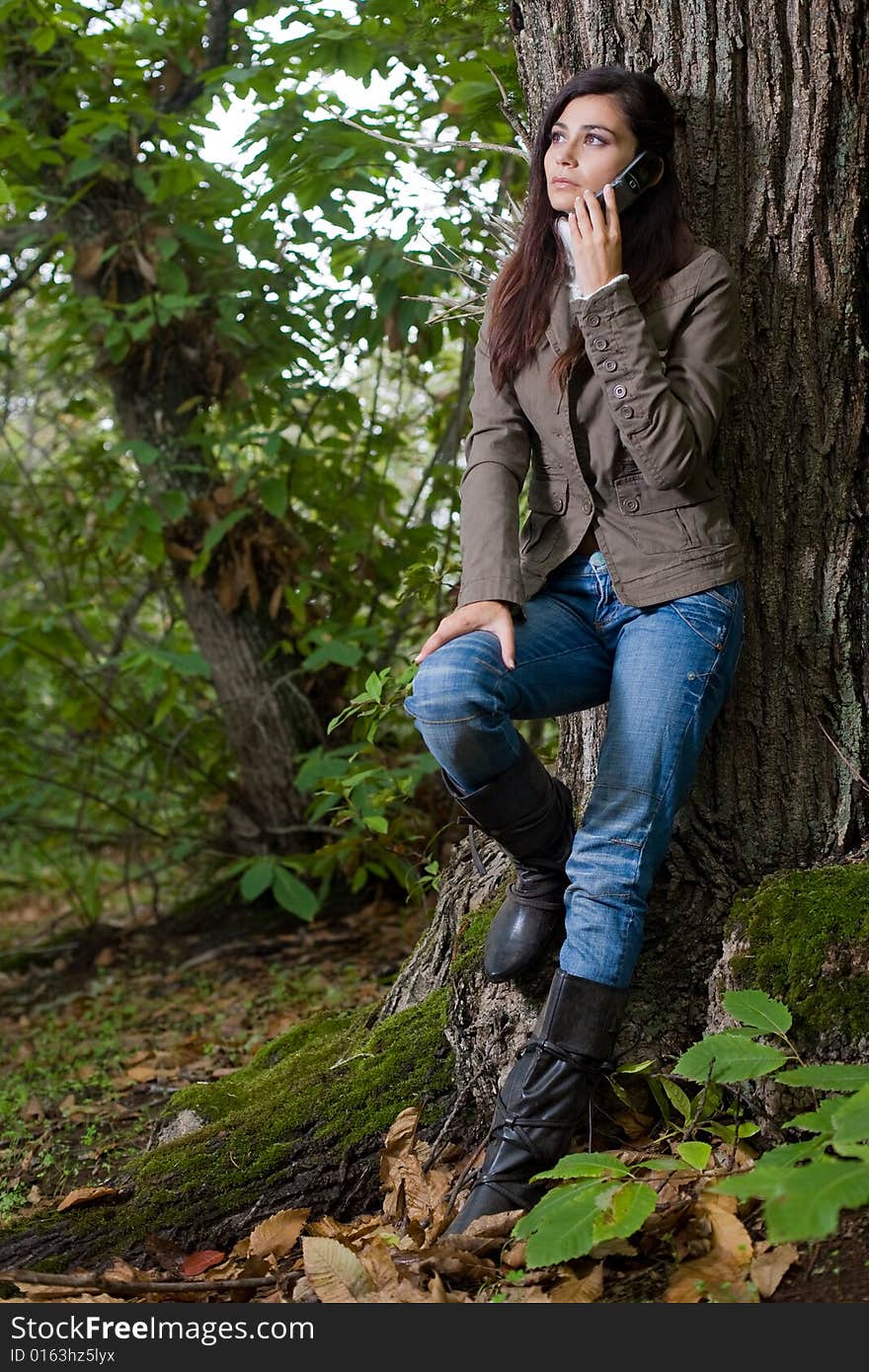 Young woman talking by phone on deep forest. Young woman talking by phone on deep forest