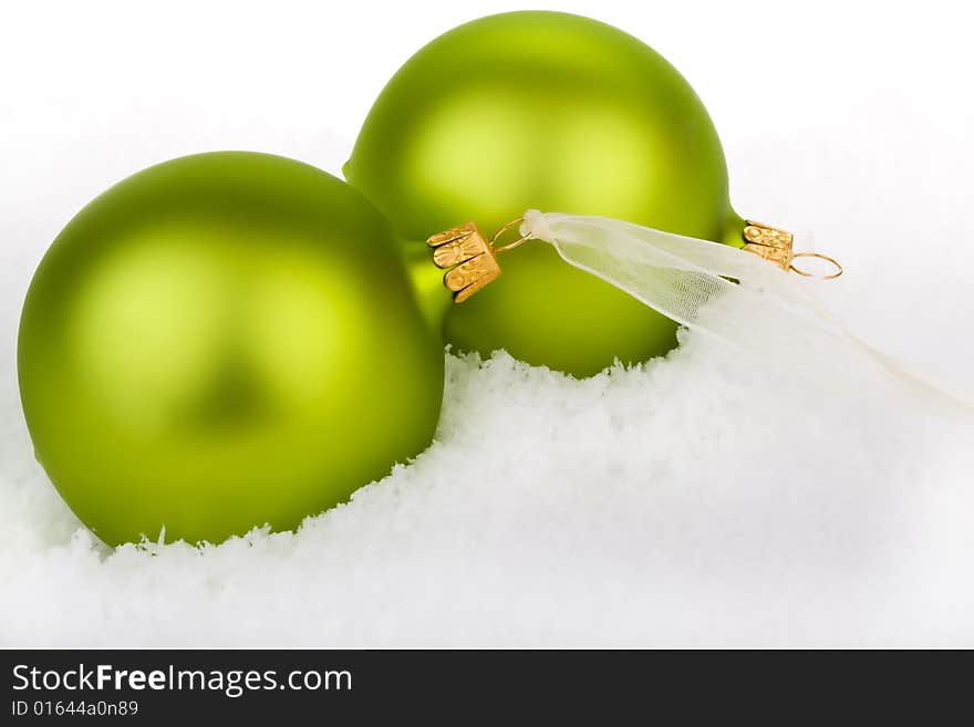 Go green this Christmas. Green Baubles on a bed of snow.