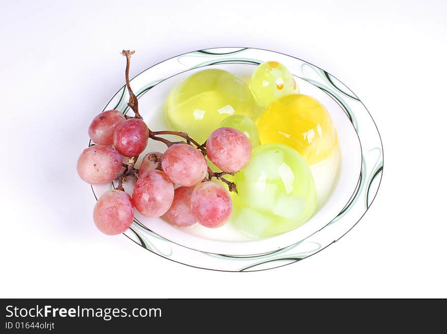 Jelly and a branch of grape in  dish on white  background. Jelly and a branch of grape in  dish on white  background